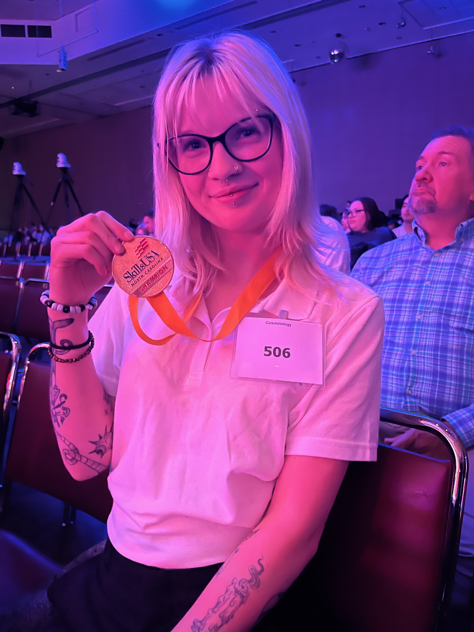 Haven Perkins holding up medal in seated area
